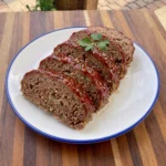 Classic homemade meatloaf sliced and glazed on a white ceramic plate