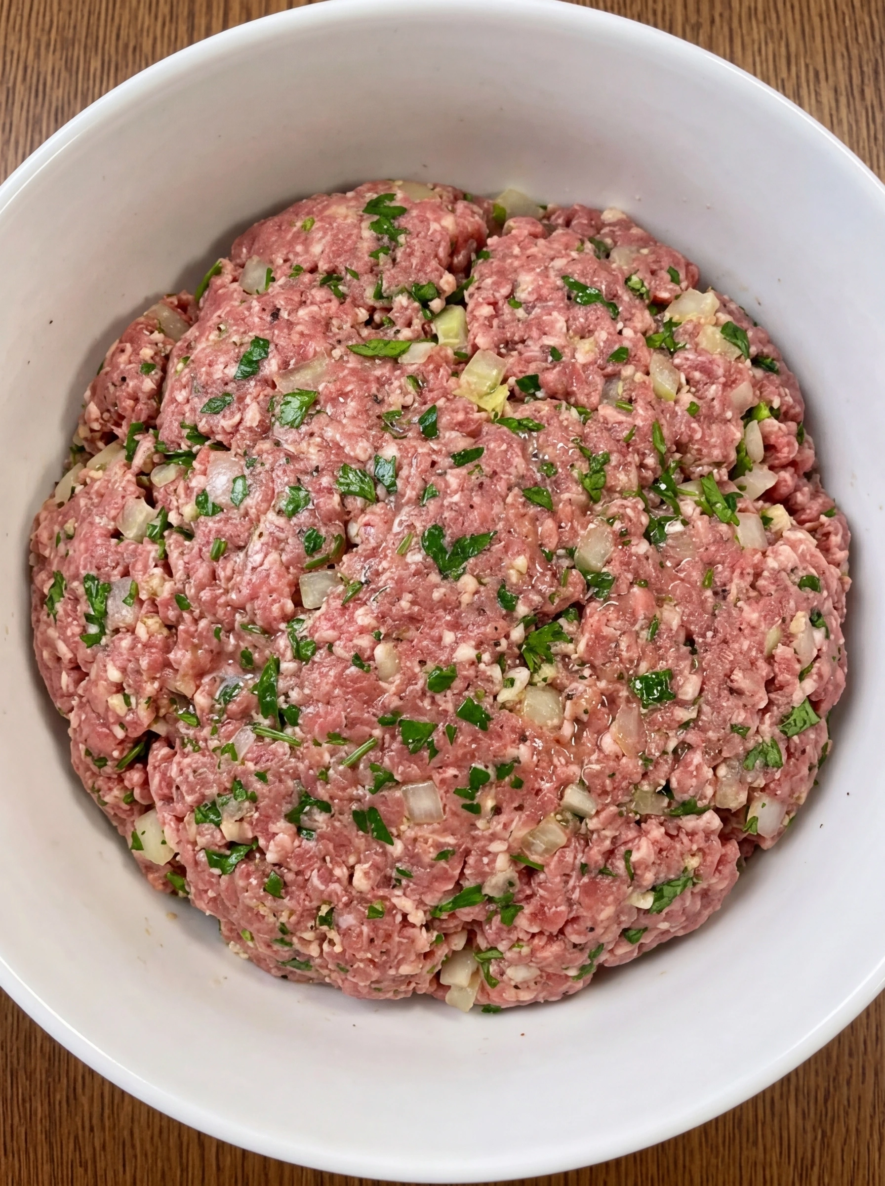 Raw meatloaf mixture combined in a white ceramic bowl