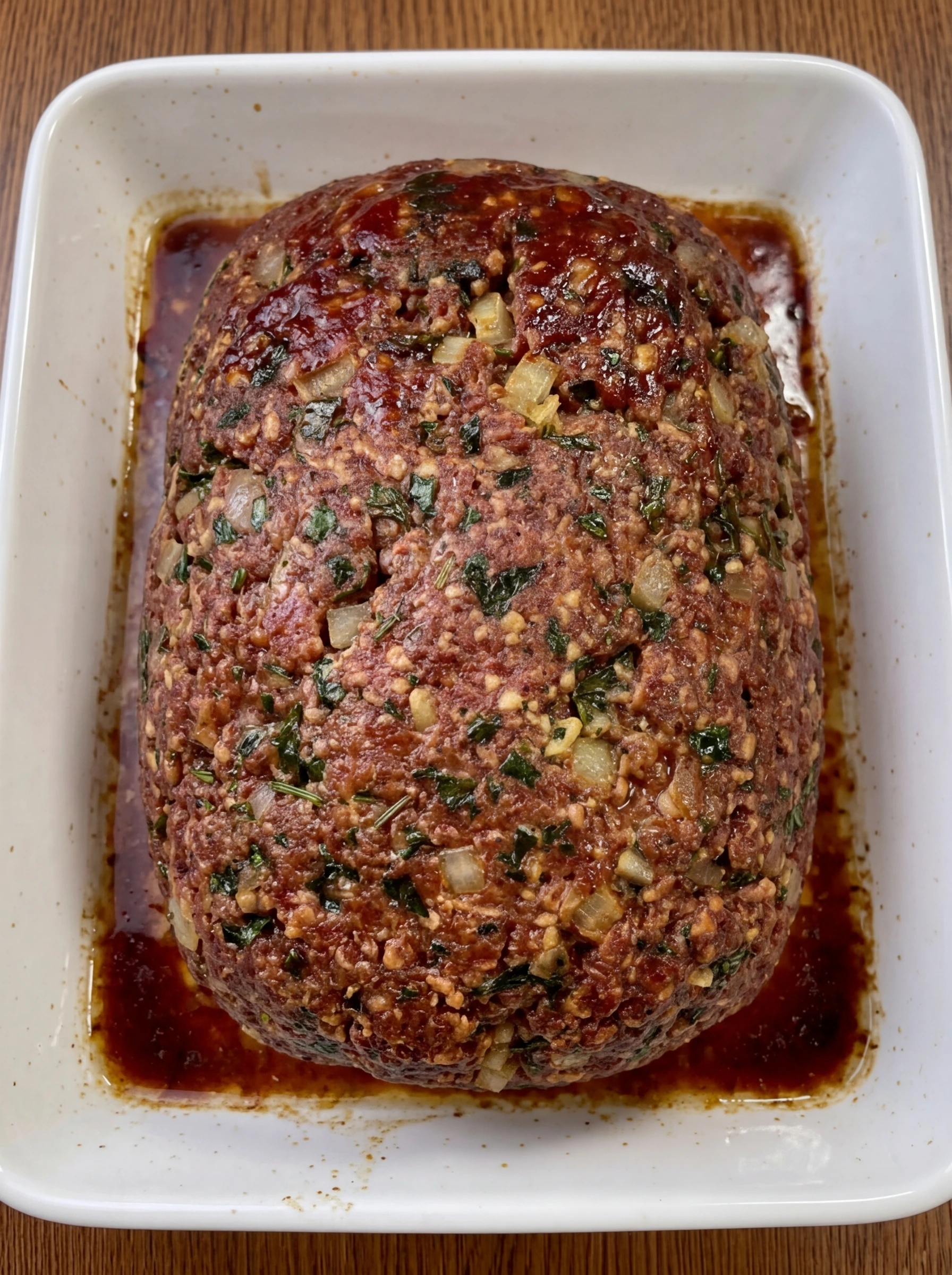 Finished meatloaf resting on a white ceramic tray