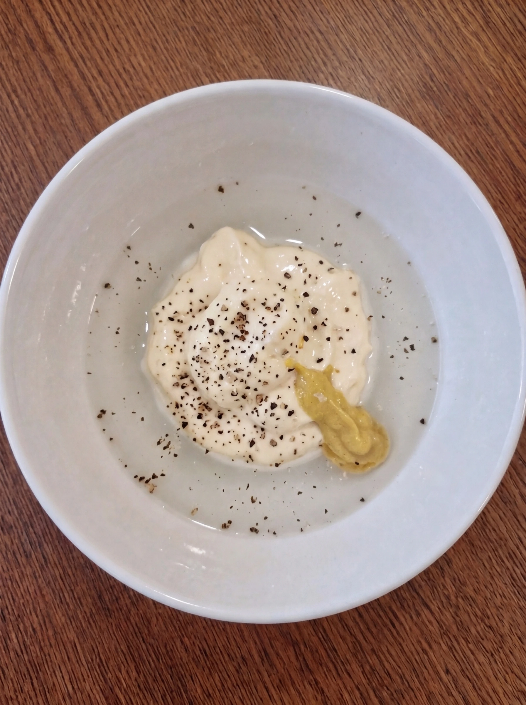 Measured tuna salad dressing ingredients in a white ceramic bowl