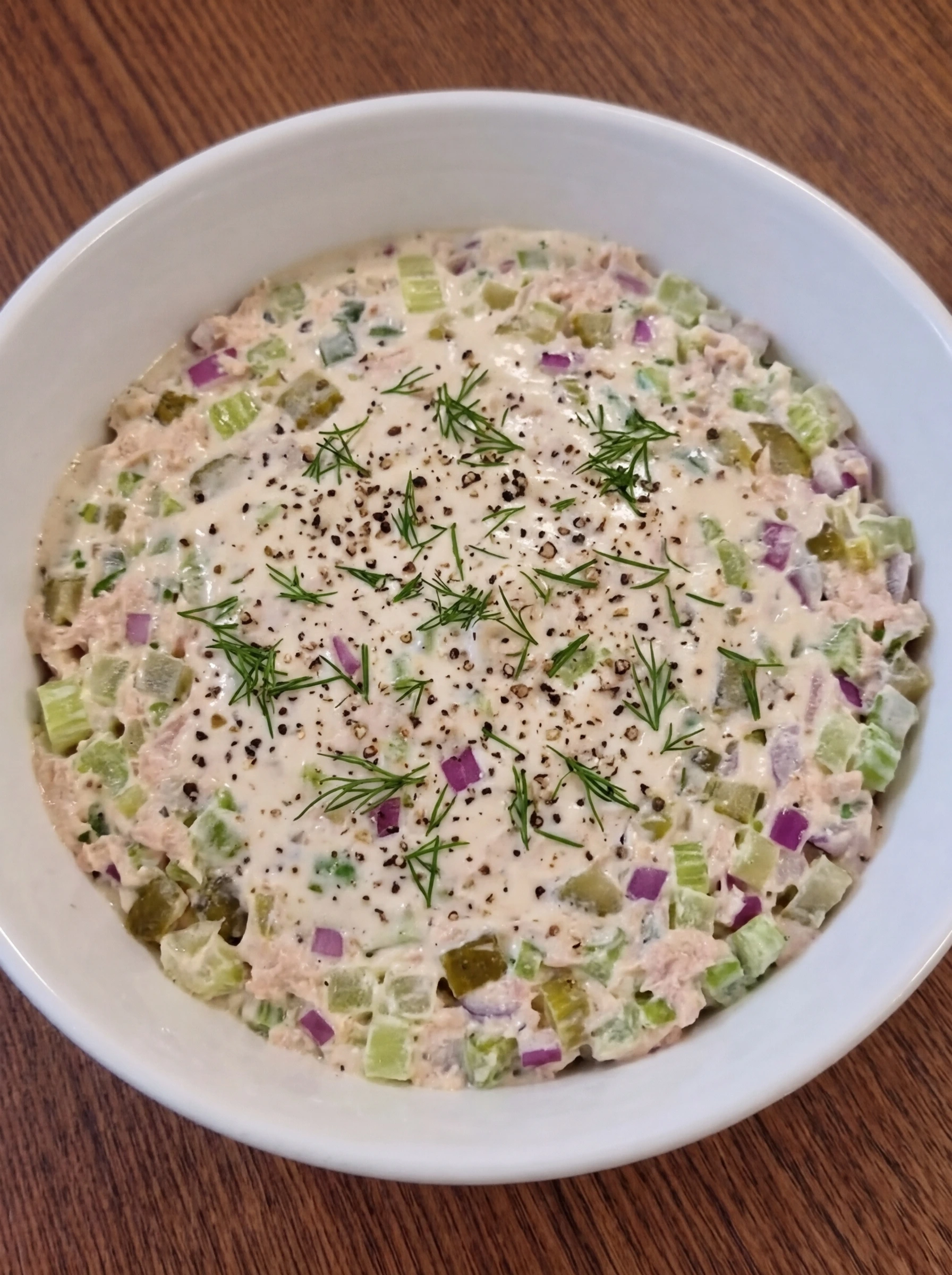 Creamy tuna salad resting in a white ceramic bowl