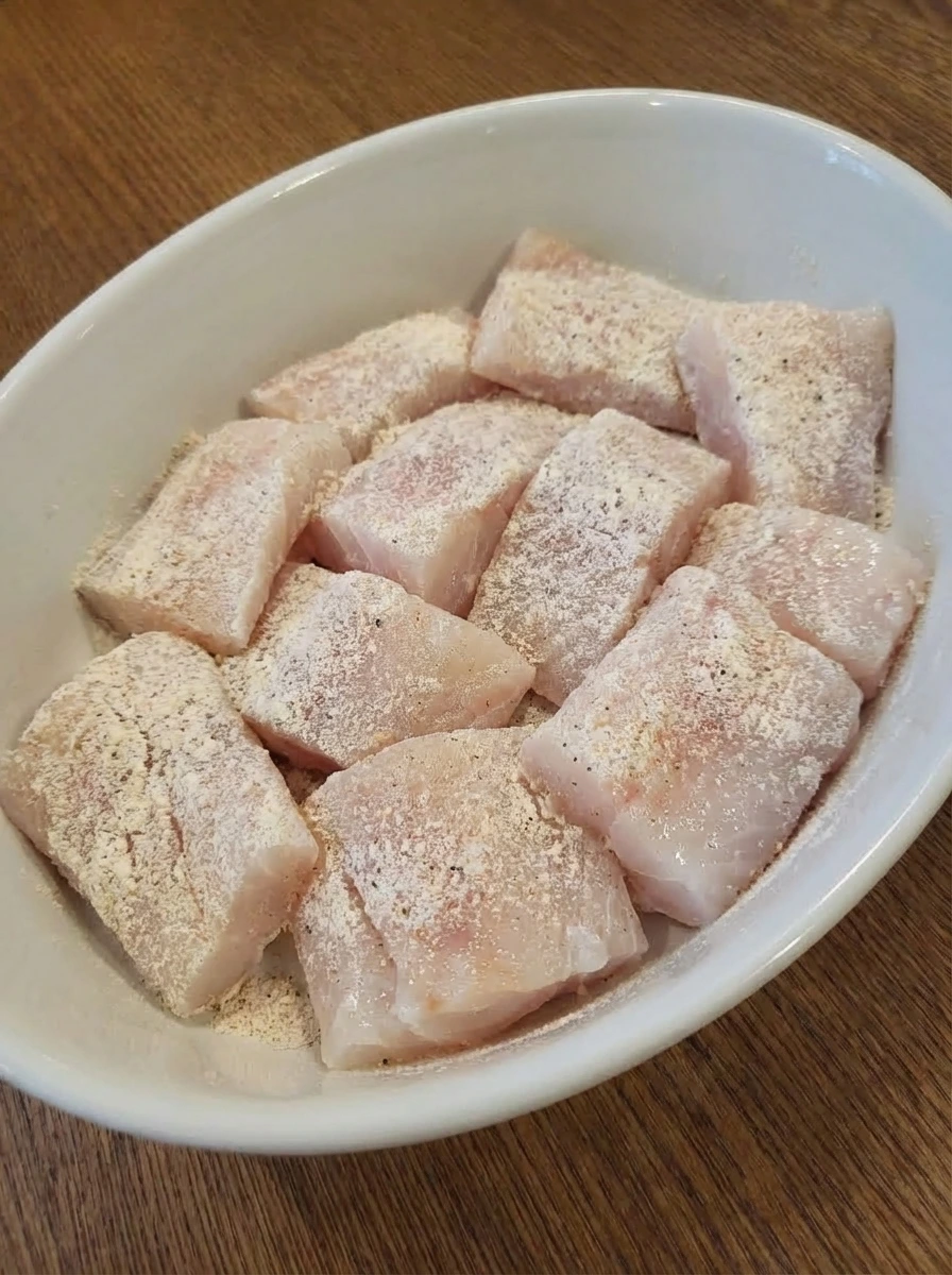 Raw cod pieces dusted with flour in preparation for battering