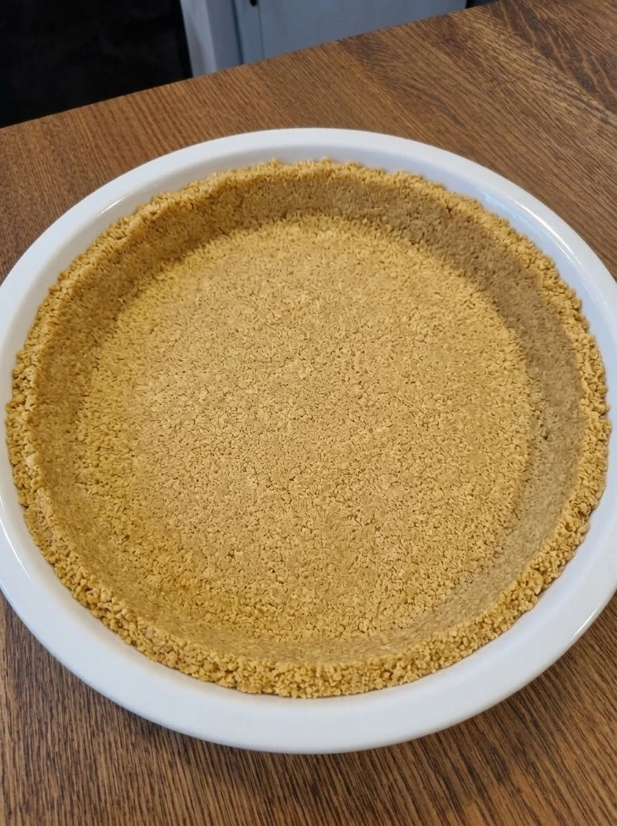 Pressed graham cracker crust in a white ceramic pie dish