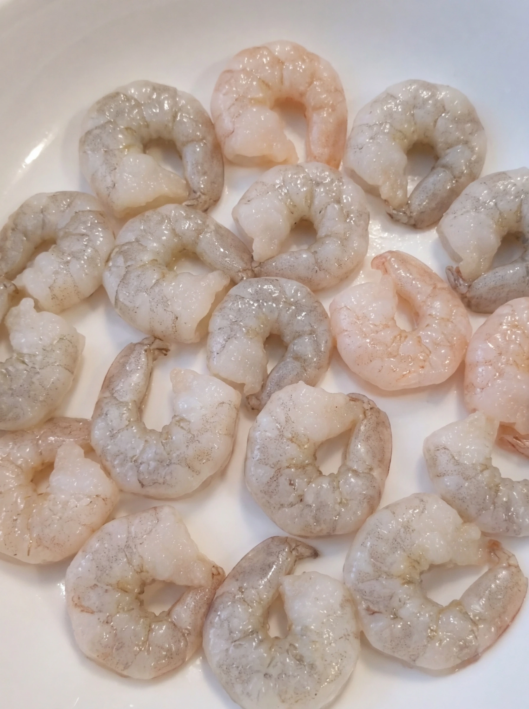 Raw cleaned shrimp in a white ceramic pasta bowl