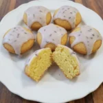 Mini lemon cakes with lavender glaze on a white scalloped dessert plate