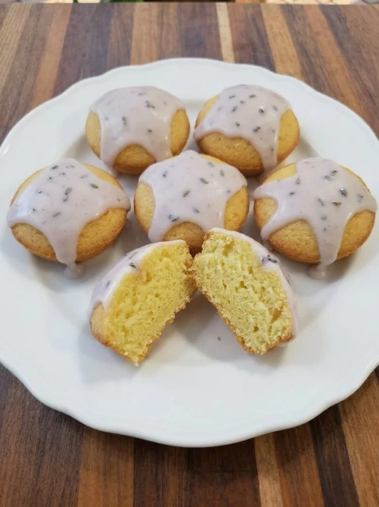 Mini lemon cakes with lavender glaze on a white scalloped dessert plate