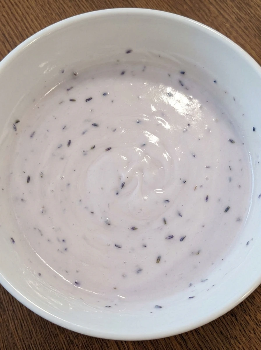 Lavender glaze mixed in white bowl for mini lemon cakes
