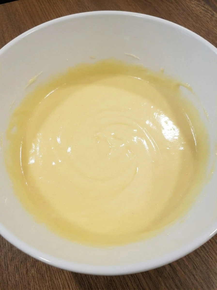 Eggs and vanilla mixed into lemon cake batter in white bowl