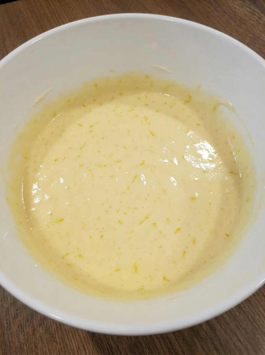 Lemon zest and juice mixed into cake batter in white bowl