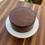 Moist chocolate cake with creamy chocolate frosting on a white ceramic cake stand
