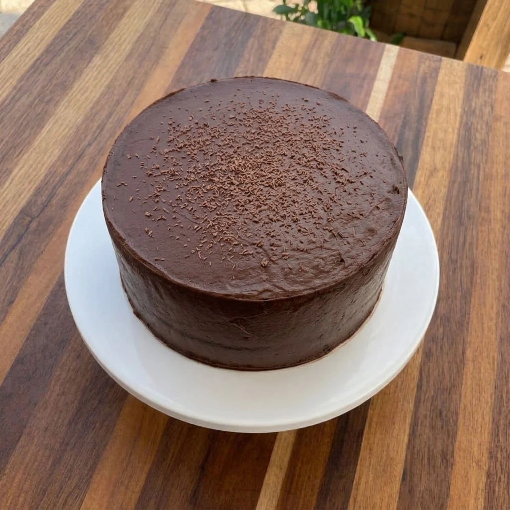 Moist chocolate cake with creamy chocolate frosting on a white ceramic cake stand
