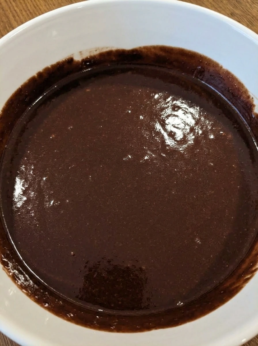 Smooth chocolate cake batter in a white ceramic mixing bowl