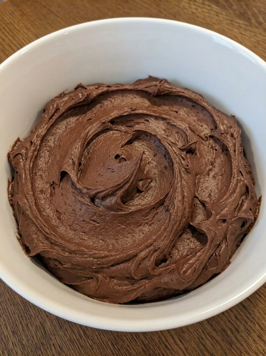 Chocolate frosting whipped in a white ceramic mixing bowl