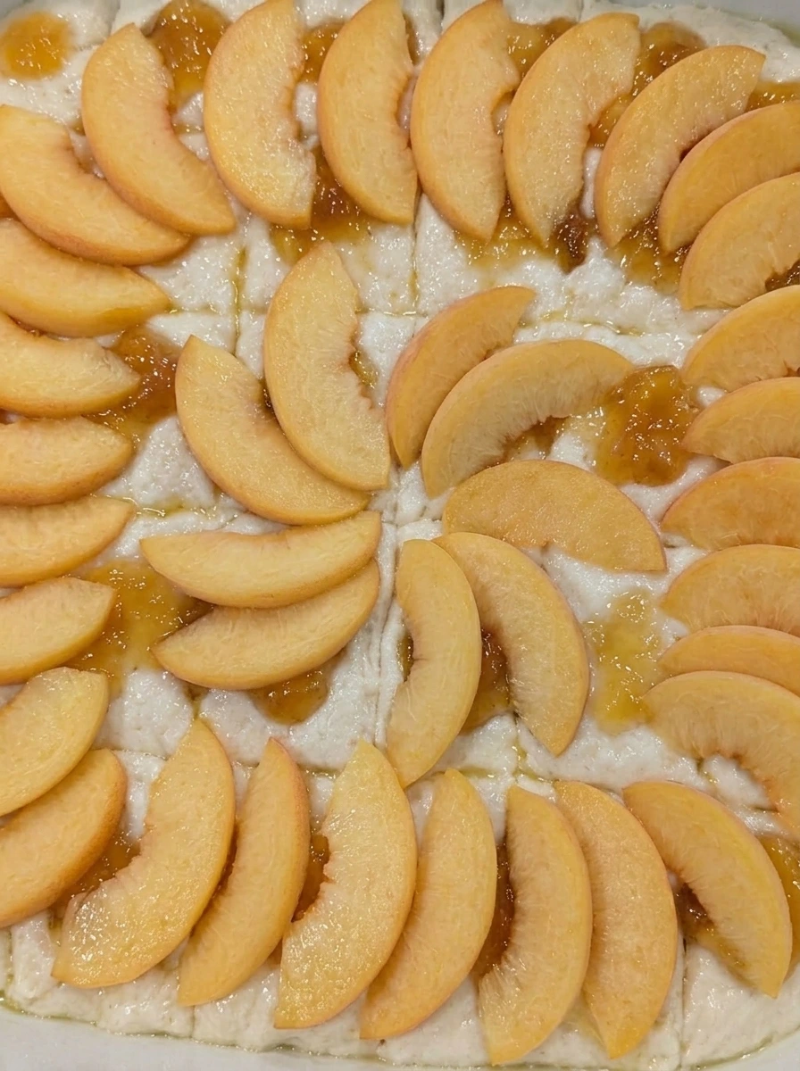 Fresh peach slices arranged over peach swirl biscuit dough