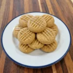 Soft peanut butter cookies stacked on a white ceramic plate