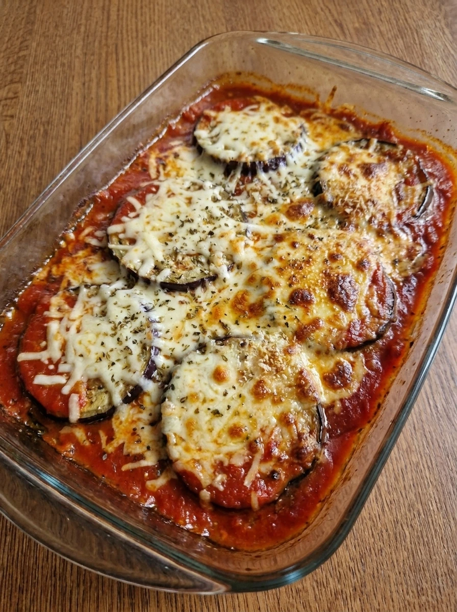 Baked Eggplant Parmesan hot from the oven with melted browned cheese.