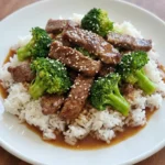 Homemade Beef and Broccoli served over white rice with glossy sauce and sesame seeds.