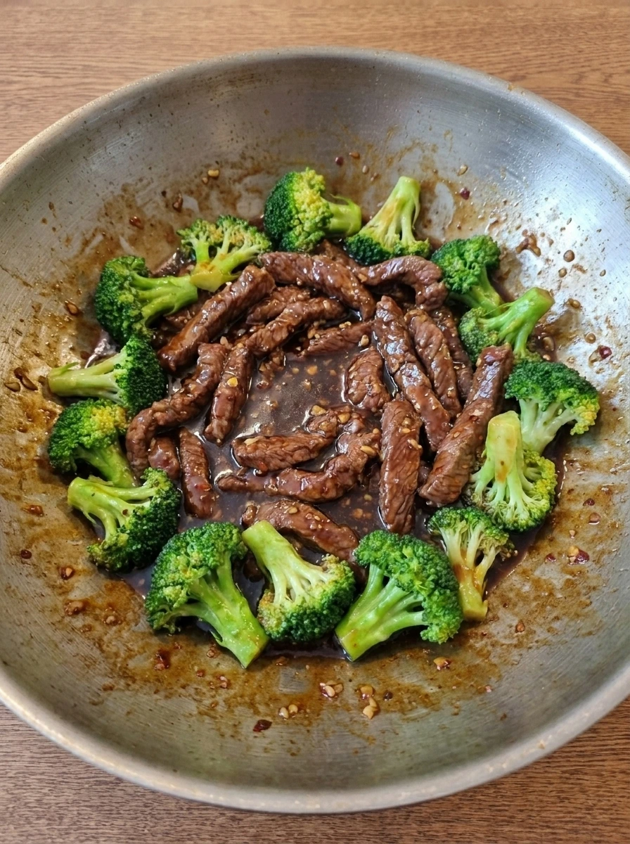 Sauce thickening around beef and broccoli in the wok.