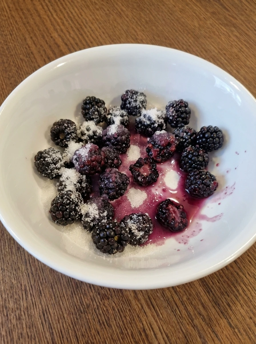Blackberries coated with sugar and lemon in a white dish