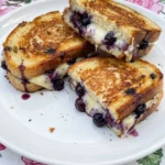 Blueberry Grilled Cheese with melted cheese and juicy blueberries on a white plate