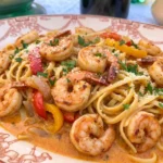 Cajun Shrimp Pasta on a white plate with creamy sauce shrimp peppers and parsley.