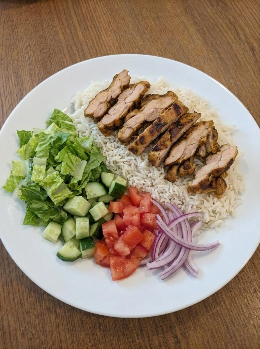 Rice salad and sliced shawarma chicken arranged on a plate