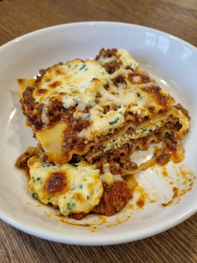 Classic Beef Lasagna on an oval white ceramic plate with melted cheese and browned edges
