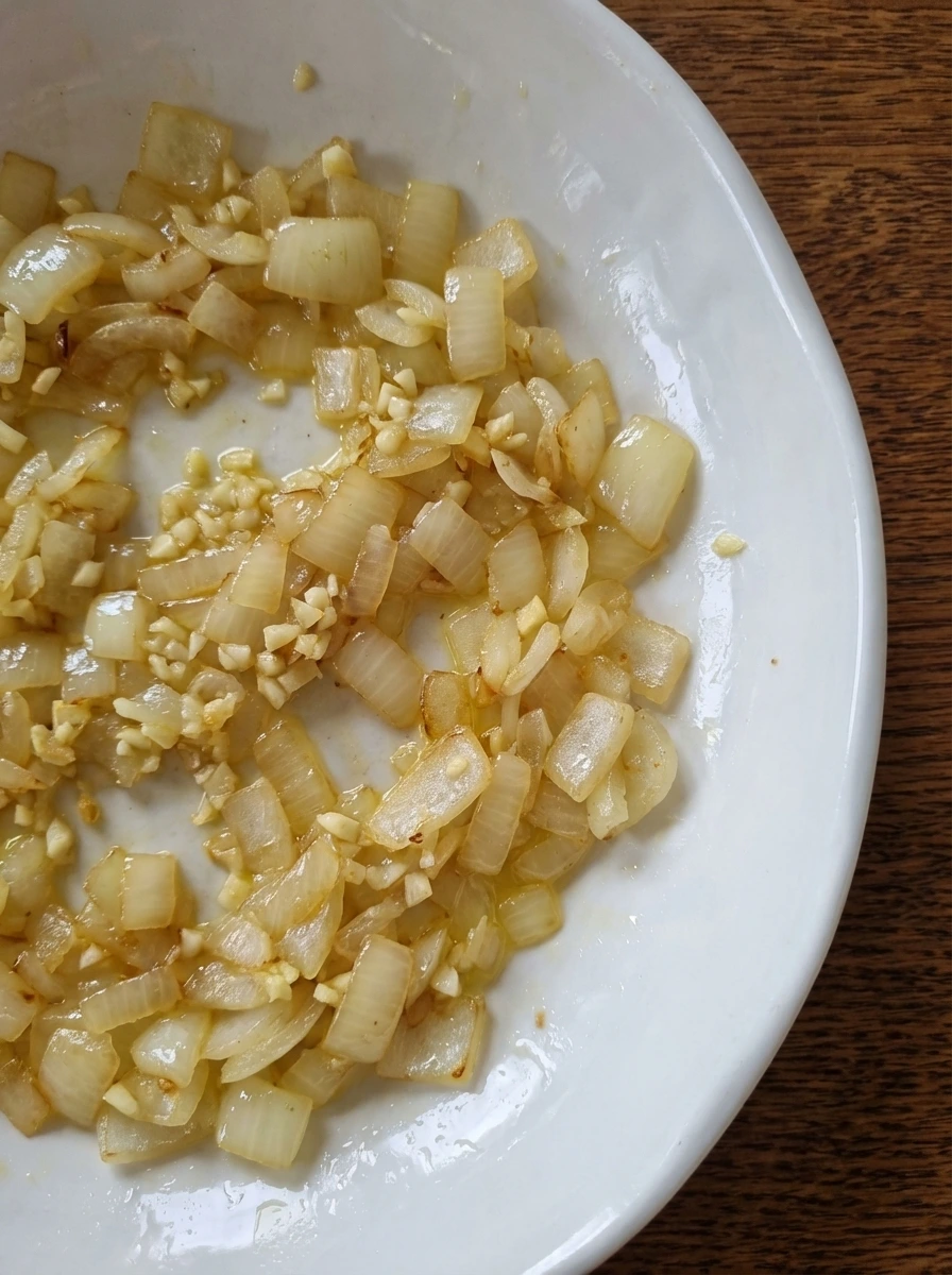 Softened onion and garlic with glossy texture in a natural white dish