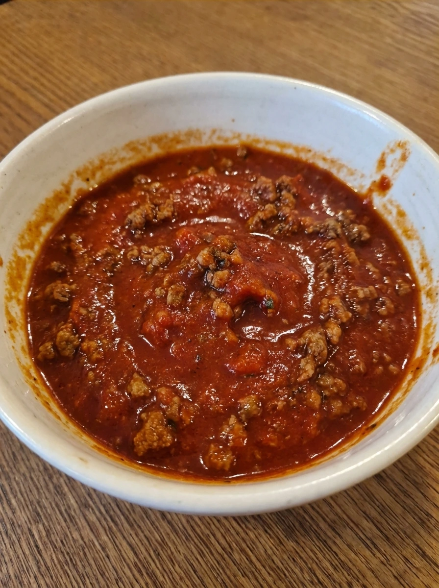 Thick beef tomato sauce with visible crumbles in a natural white dish