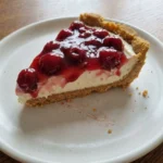 Classic Cherry Delight with creamy layers and glossy cherry topping on a round white stoneware dessert plate