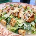 Classic Chicken Caesar Salad on a white ceramic plate with golden chicken creamy dressing croutons and Parmesan