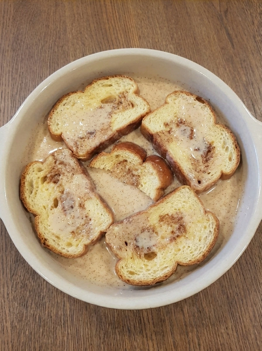 Brioche slices soaking on one side in custard for Classic French Toast