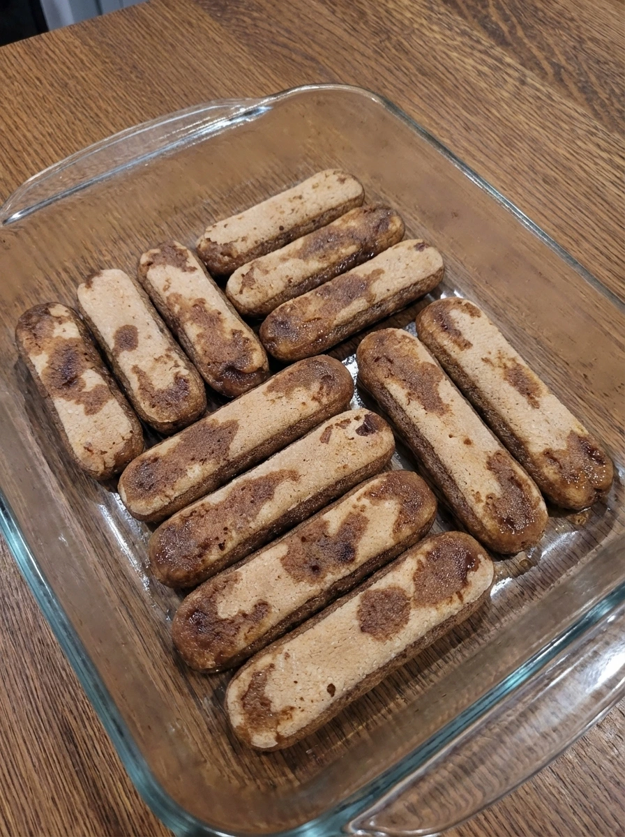 Coffee soaked ladyfingers arranged in a dish for tiramisu.