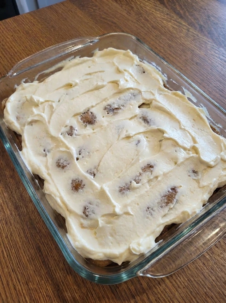 Layered mascarpone cream and ladyfingers in tiramisu dish.
