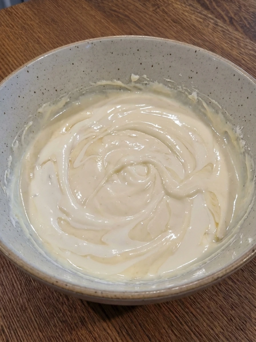 Glossy cheesecake filling after mixing in sour cream cream vanilla and lemon juice