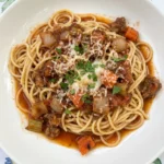 Classic Spaghetti Bolognese plated on a shallow white ceramic pasta plate with rich meat sauce and grated Parmesan