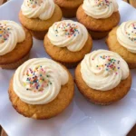 Classic Vanilla Cupcakes with creamy vanilla frosting on a white scalloped dessert plate