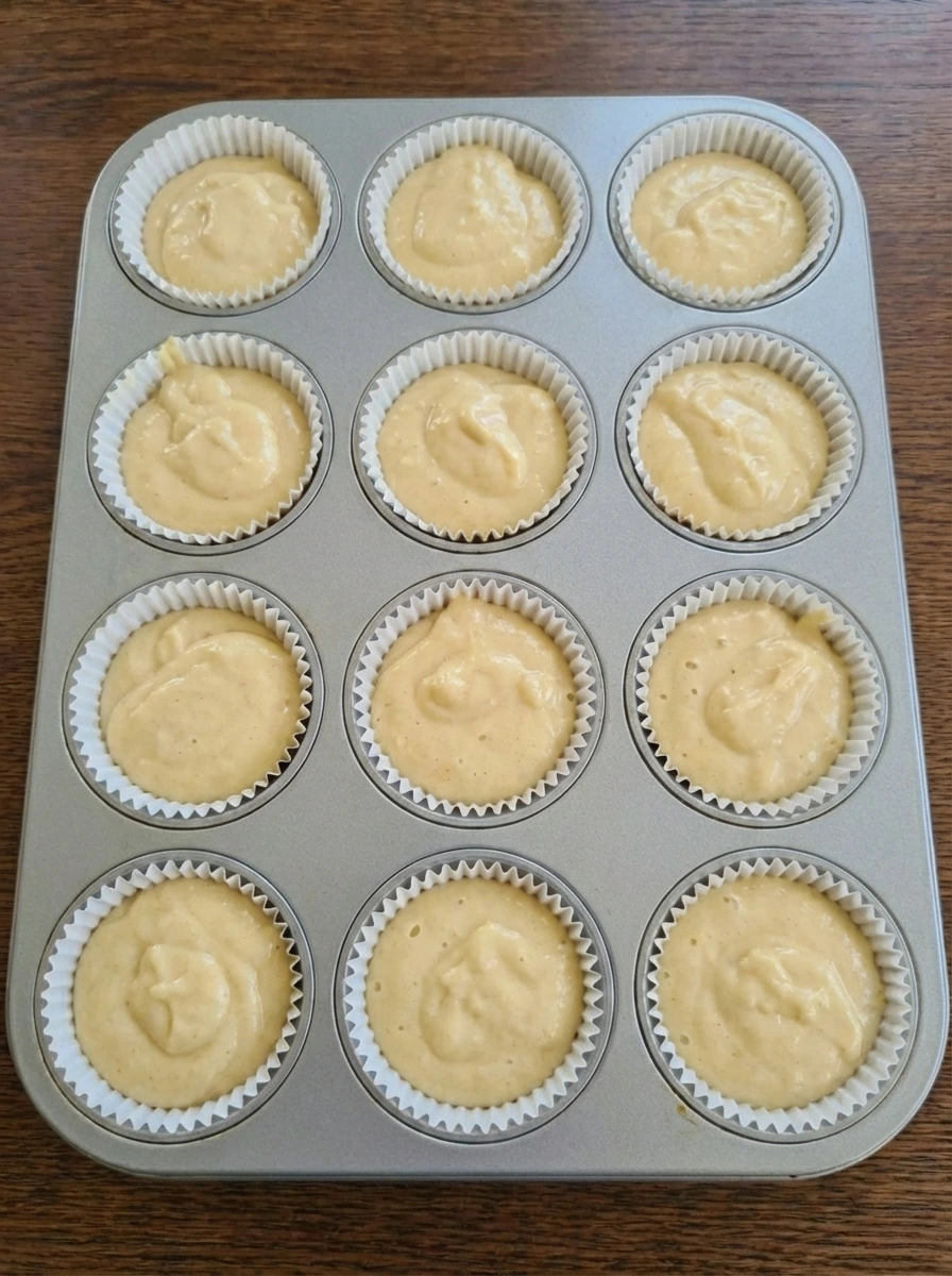 Vanilla cupcake batter portioned into lined muffin cups