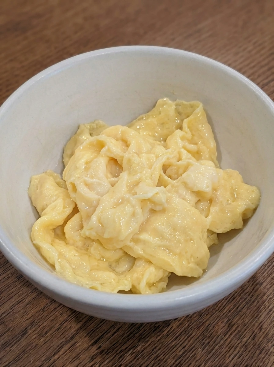 Soft folded eggs for Egg and Cheese Breakfast Sandwich in a white dish