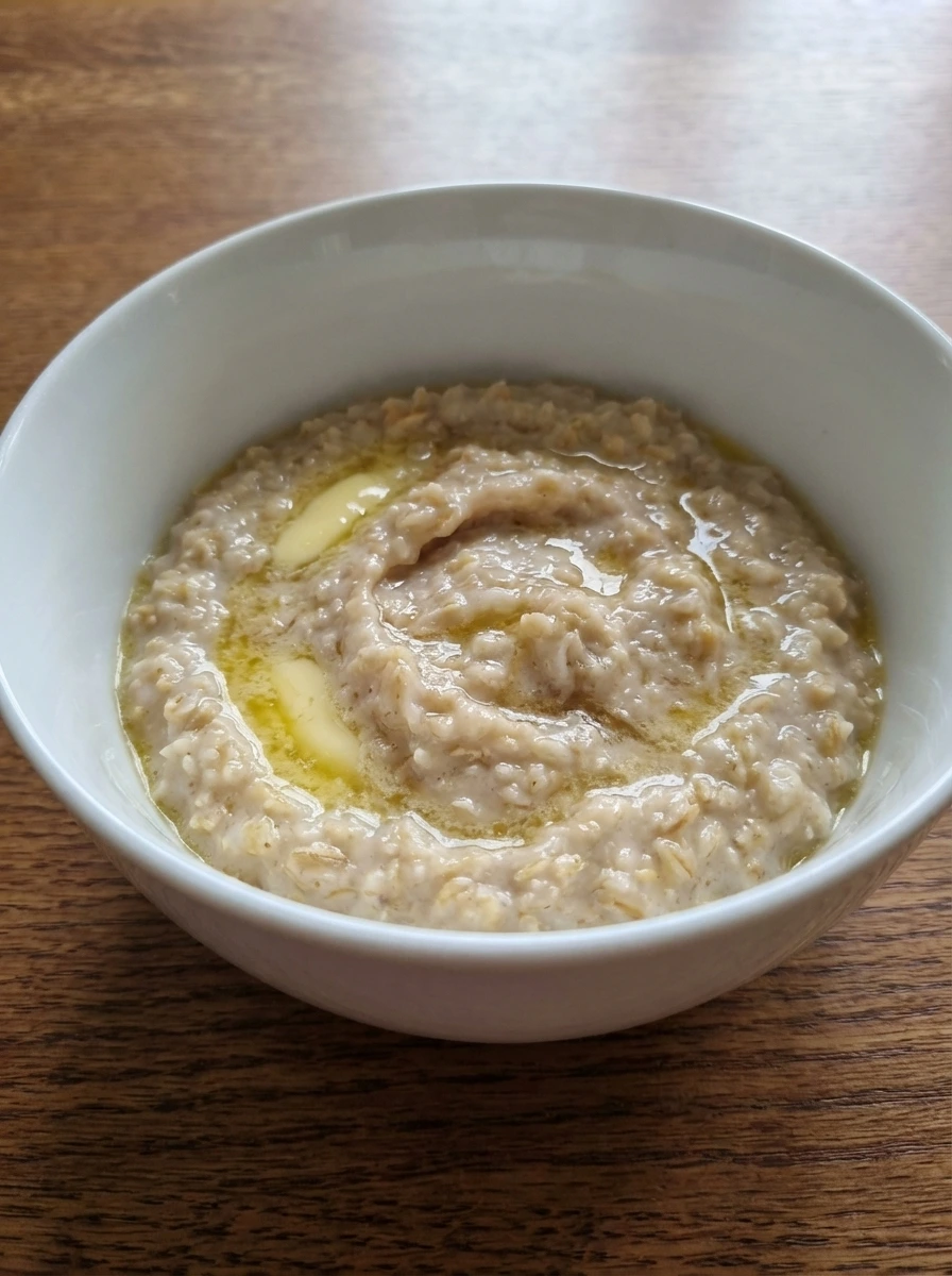 Butter melting into thick oatmeal in a natural white dish