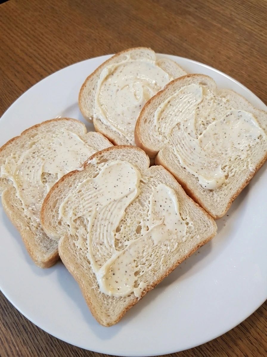 Bread slices coated with seasoned spread for grilled cheese