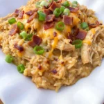 Crockpot Crack Chicken and Rice served on a white plate with bacon cheddar and green onions.