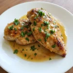Crockpot Garlic Butter Chicken served on a white plate with glossy garlic butter sauce and fresh parsley