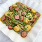 Crockpot Kielbasa and Green Beans with potatoes and parsley in a serving dish