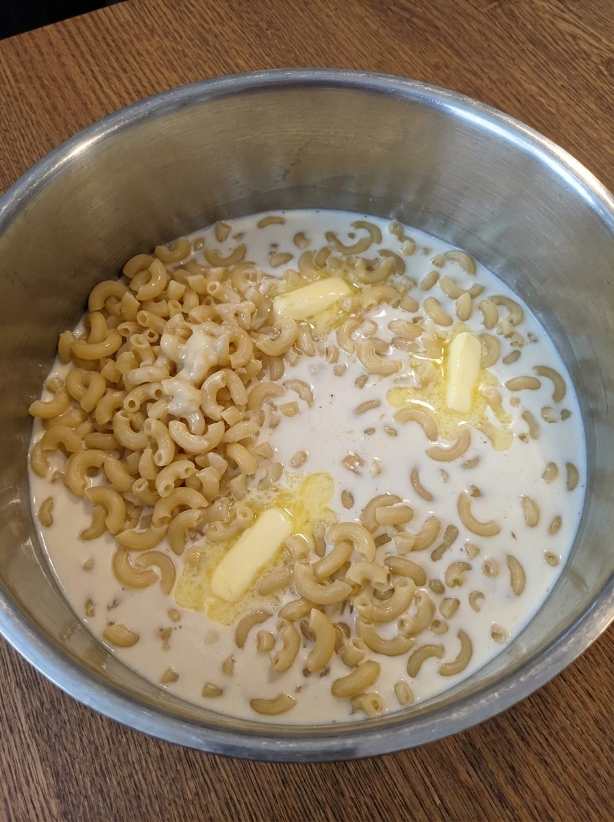 Elbow macaroni coated with milk and butter for Crockpot Mac and Cheese.