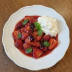 Crustless Fresh Strawberry Pie on a scalloped white ceramic dessert plate with glossy strawberries and whipped cream