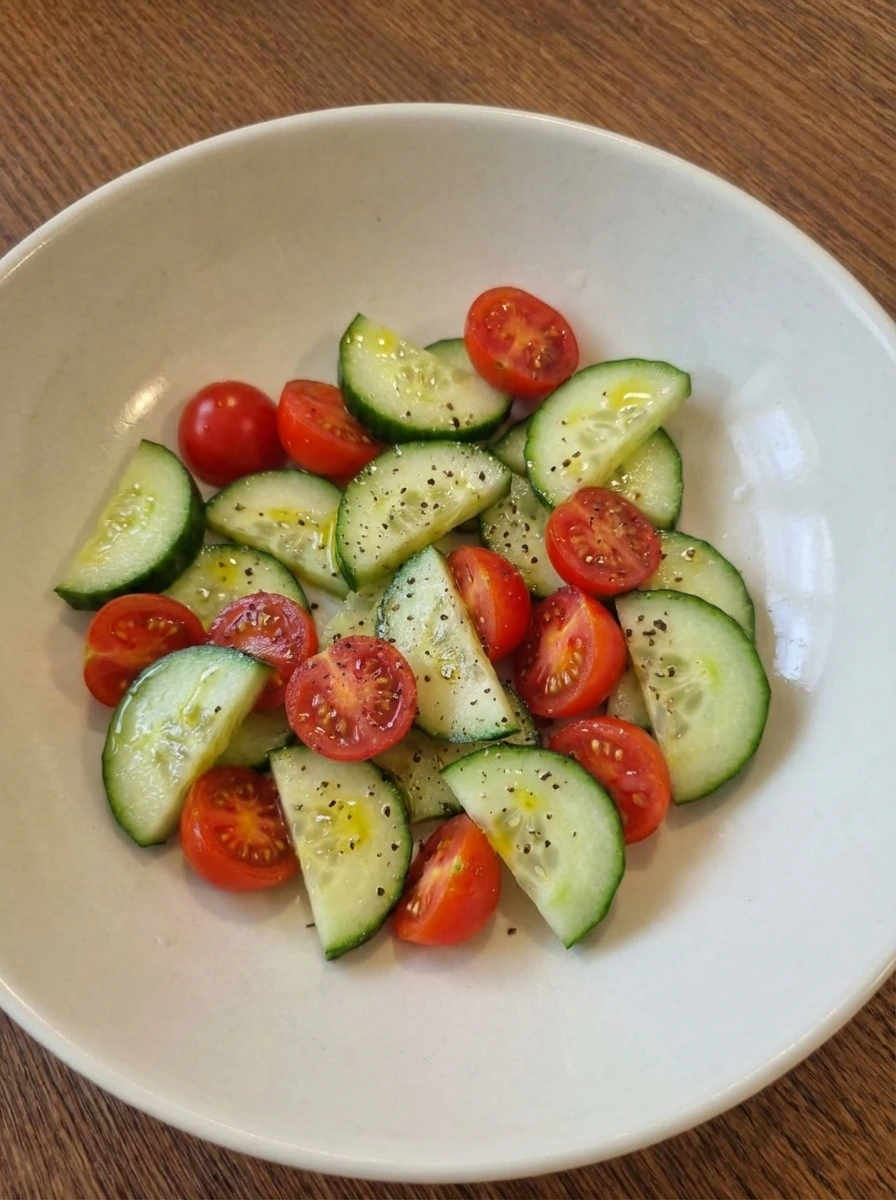 Cucumber and tomatoes lightly coated with dressing in a bowl