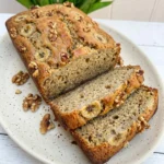 Easy Banana Bread sliced on a speckled oval cream ceramic plate with a golden brown crust and moist crumb.