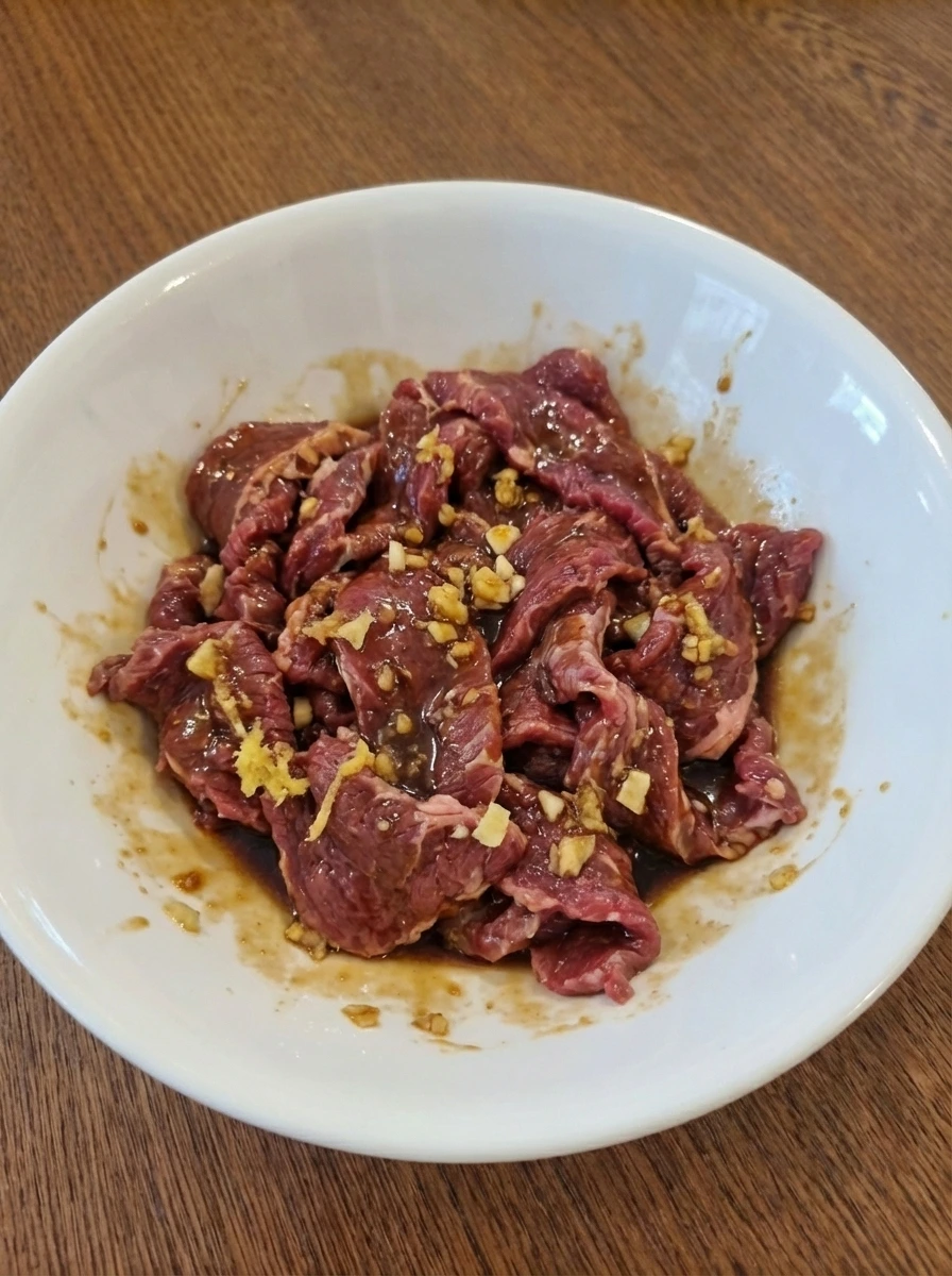 Raw beef marinating with sauce garlic and ginger in a white bowl