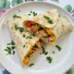 Easy Chicken Wrap on a white speckled plate with browned chicken melted cheese lettuce tomato and parsley